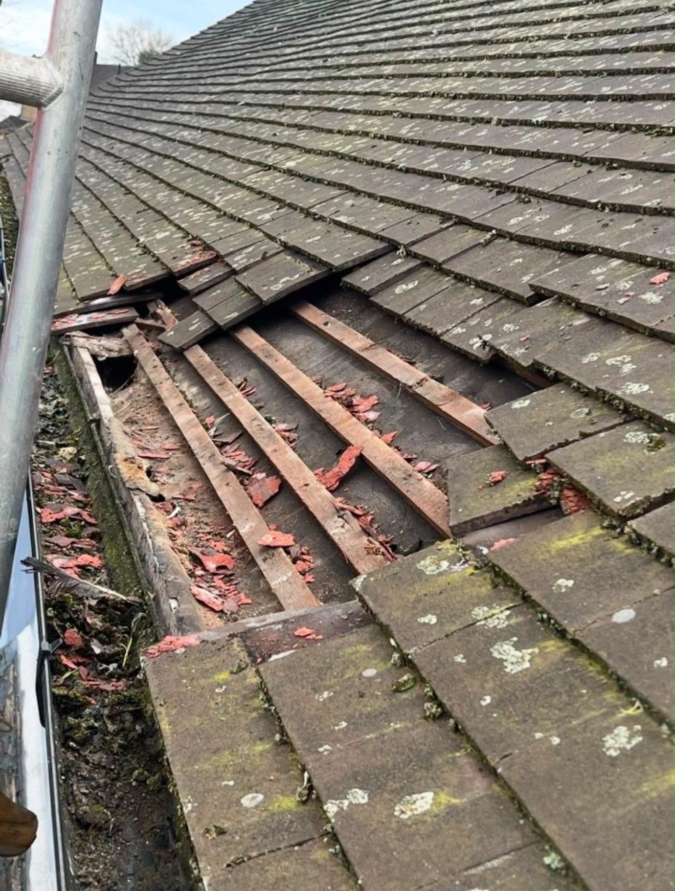 Storm-damaged roof with slipped and broken tiles exposing the battens